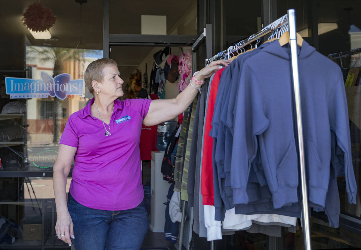 Michele Walker, owner of Imaginations Unlimited, organizes clothes out on the sidewalk to visua ...